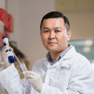 Dr Joohyung Lee, Honorary Research Associate, working at the lab bench and using a microscope to assist with his medical research