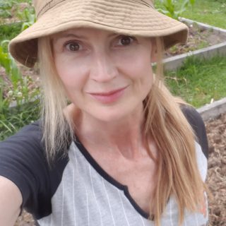 Imelda, wearing a hat and working in the garden.