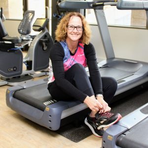 Professor Elizabeth Hartland ties her shoe laces as she's sitting on treadmill