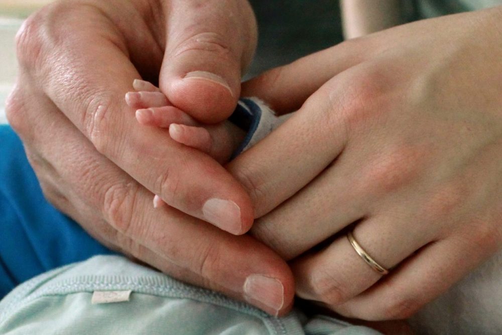 Dani and Darren holding their precious little baby Jack's hand.