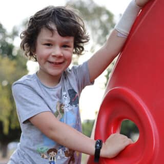 Luca Boggia rare brain tumor survivor playing in a park and laughing