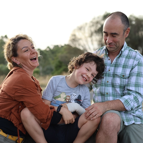 The Boggia family of L:R Monique, Luca (rare childhood brain cancer survivor) and Baden Boggia in a park laughing