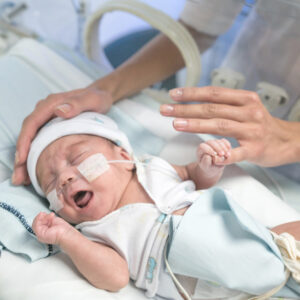 Preterm baby in hospital holding mums finger